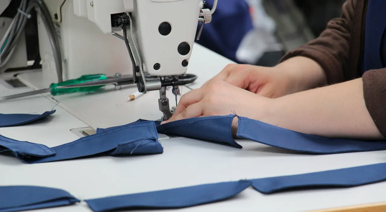 Operator stitching indigo panels at a sewing station